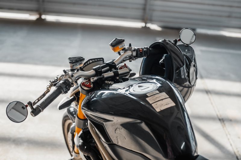 Closeup image of a black motorcycle with helmet resting on handlebar